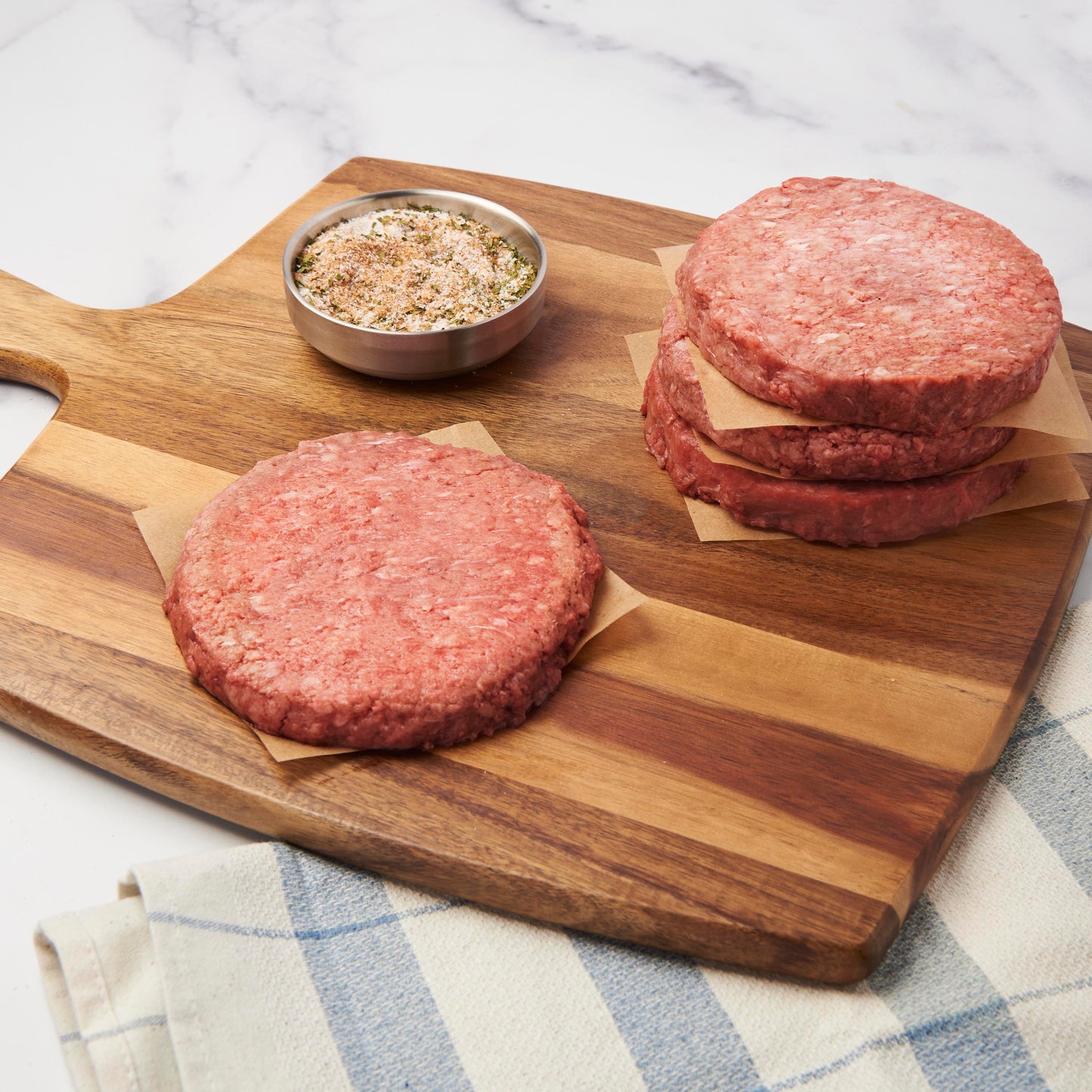 Raw A5 Blend Burgers on cutting board with salt ready to be cooked