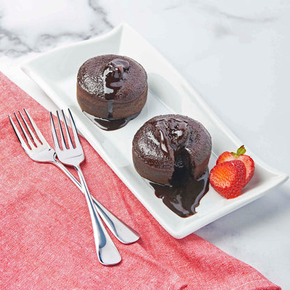 2 cooked lava cakes with chocolate oozing out onto plate