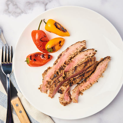 Fully cooked flank steak, sliced and on a plate ready to be eaten.