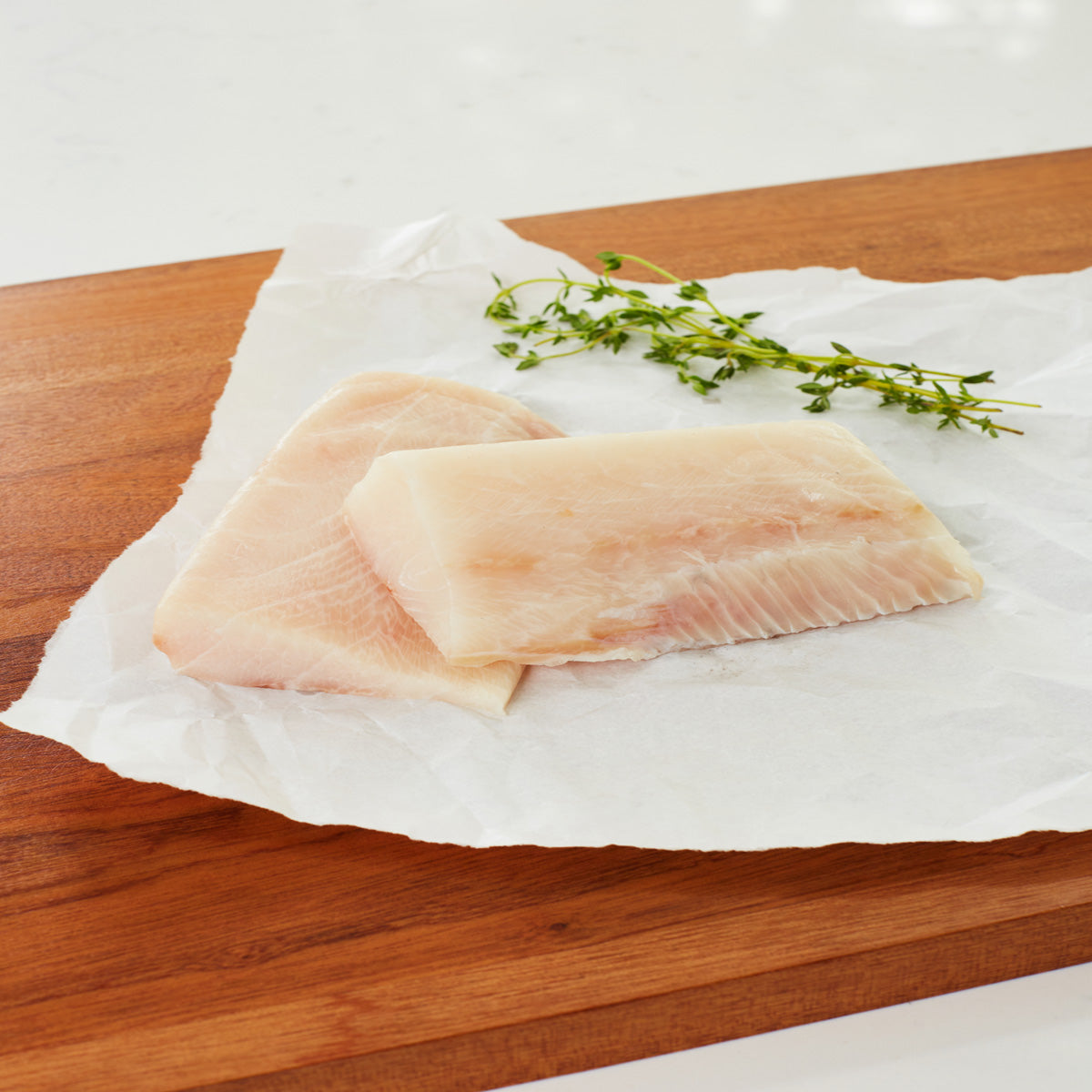 2 raw cobia filets on a cutting board ready to be cooked.