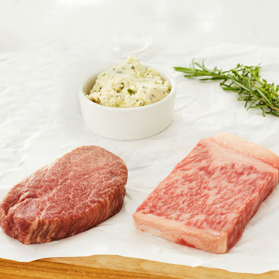 Raw A5 Japanese Wagyu 5oz Filet and 5 oz New York Strip with butter on a board ready to be cooked.